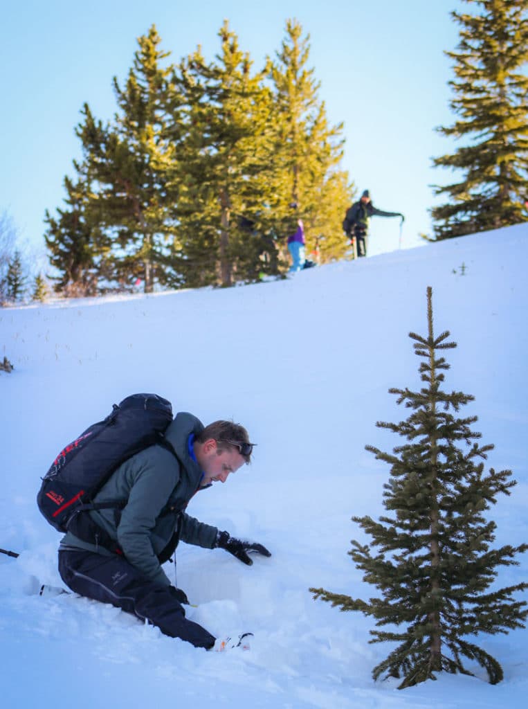 avalanche science student practicing a beacon search in an avalanche rescue class while two instructors oversee