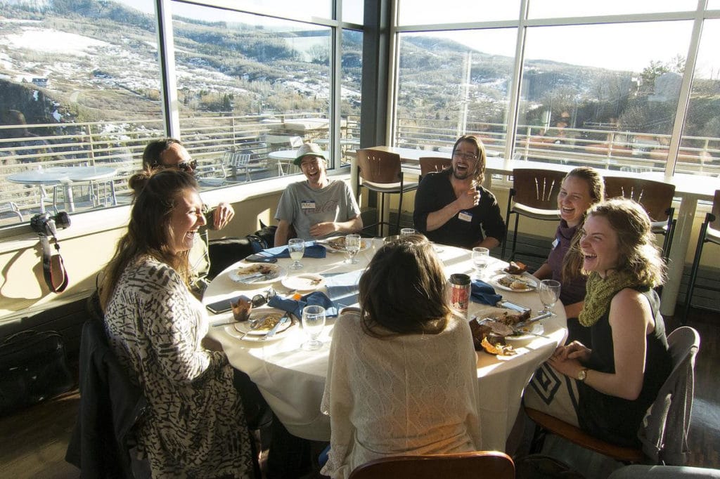 Participates laugh around a dining hall table at CMC Steamboat Springs during a Sustainability Conference.