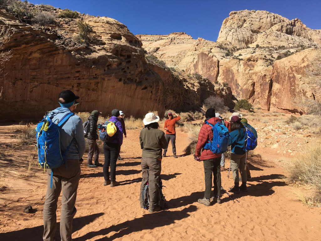 CMC Outdoor Education instructor teaches students on a canyon hike during a desert orientation trip.