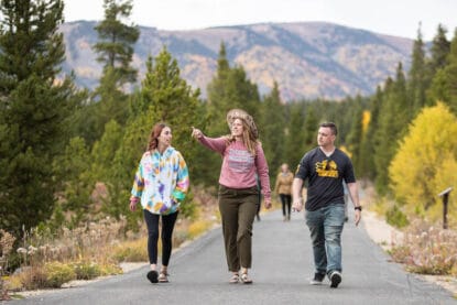 Three CMC Leadville students walk on a paved bike path on a fall day.