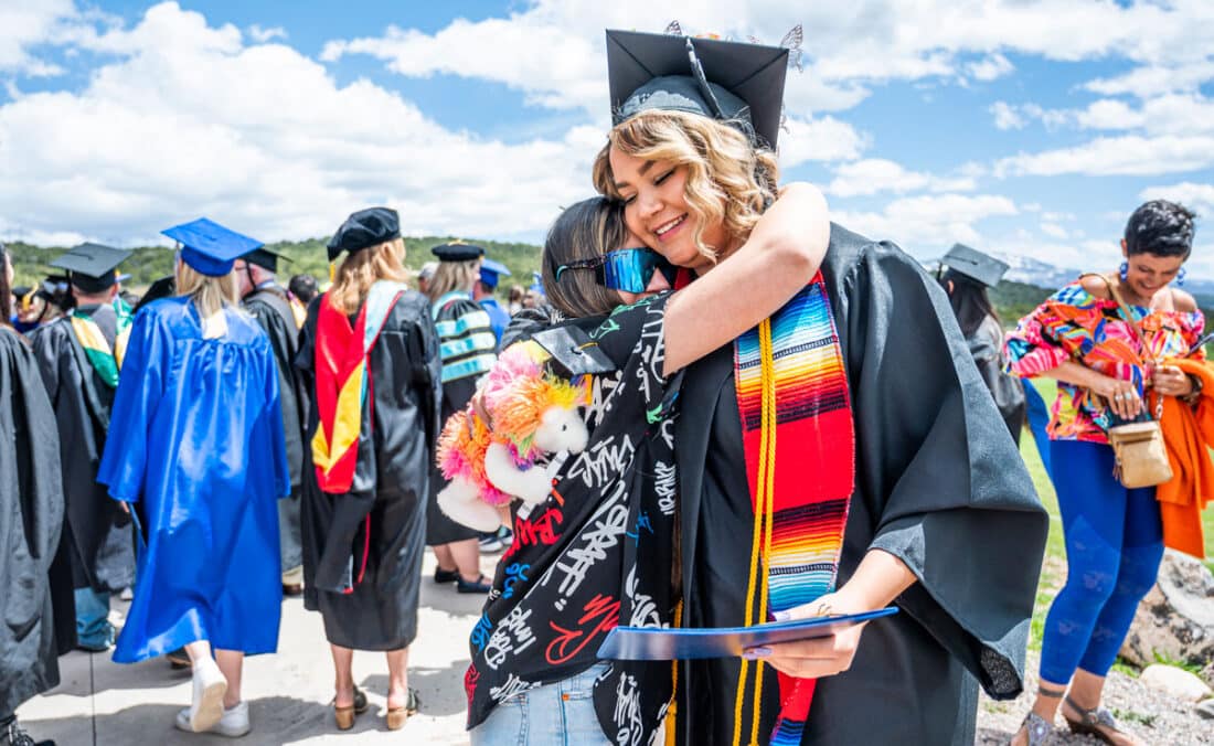 A latina CMC students gets a hug after her commencement ceremony.