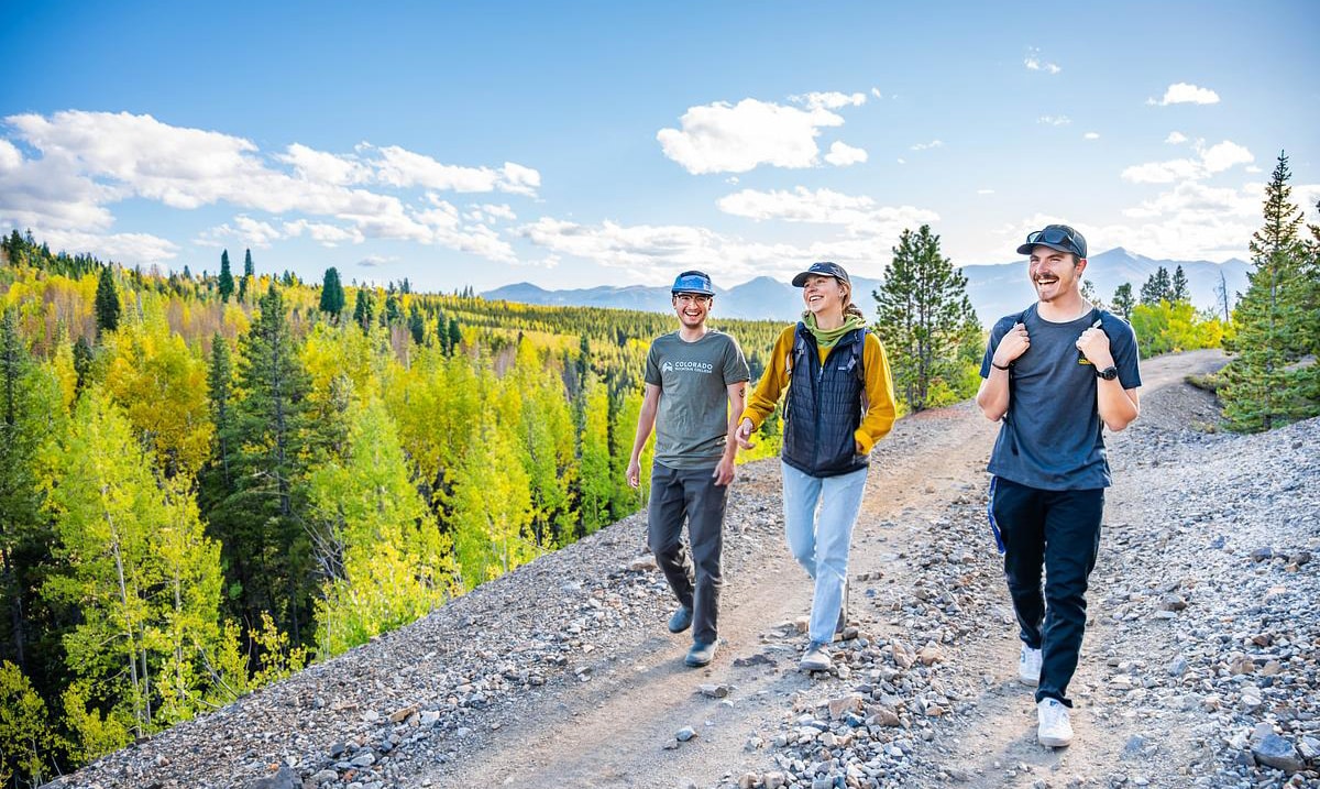 Three CMC students hiking on a dirt road near the CMC Leadville campus.